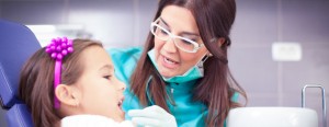 Female hygienist examining a young girl's teeth