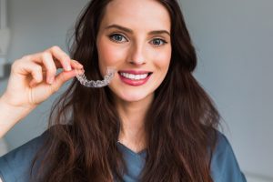 woman holding invisalign clear aligner