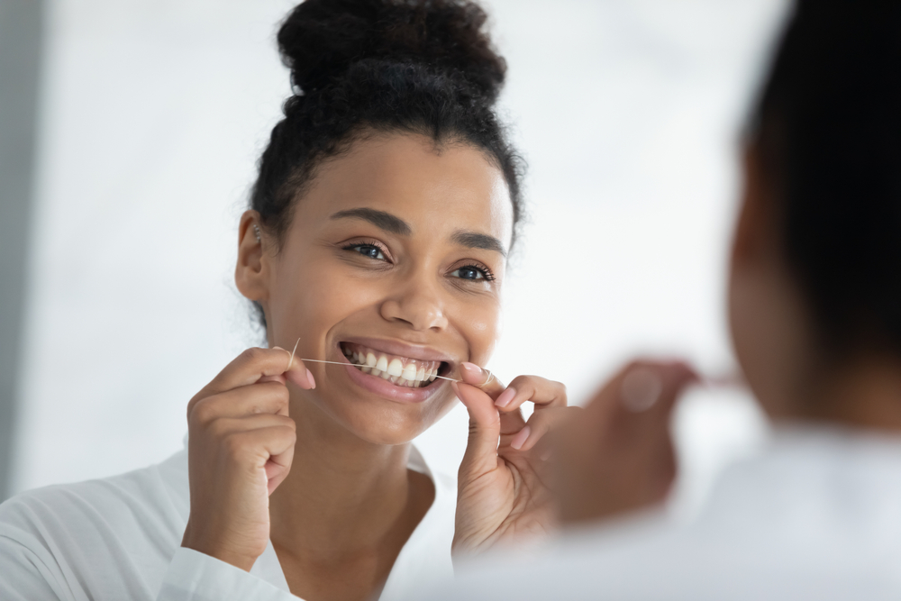 young woman flossing her teeth